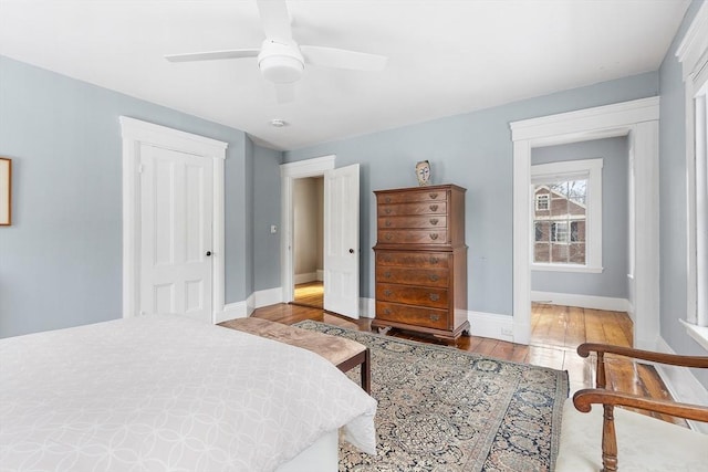 bedroom featuring a ceiling fan, a closet, baseboards, and wood finished floors