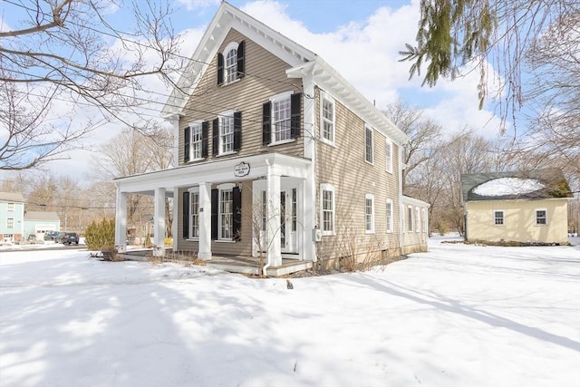 snow covered property with covered porch