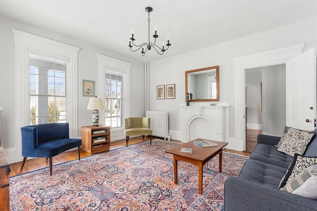 living room with radiator, an inviting chandelier, baseboards, and wood finished floors