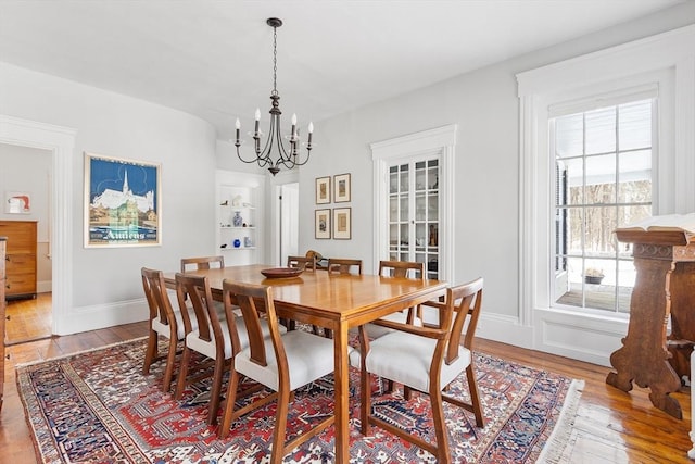 dining area featuring a chandelier, light wood finished floors, and baseboards