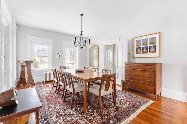 dining room featuring radiator, baseboards, a chandelier, and wood finished floors