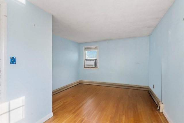 spare room with light wood-type flooring, cooling unit, and a baseboard heating unit