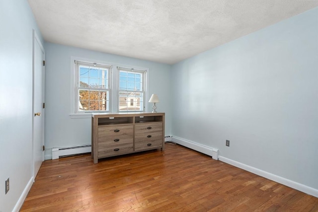 bedroom with baseboard heating, hardwood / wood-style floors, and a textured ceiling