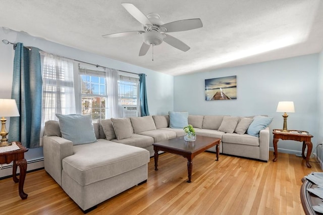 living room featuring ceiling fan, a baseboard heating unit, and light hardwood / wood-style flooring