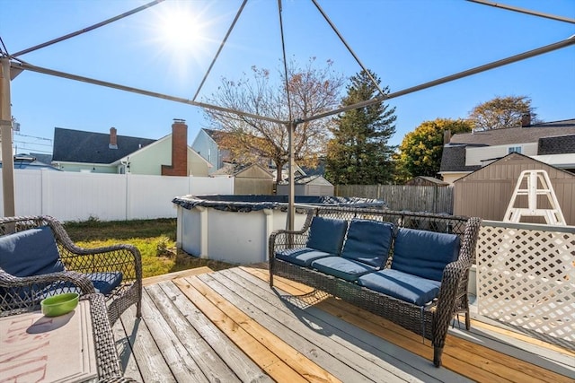 wooden deck featuring a covered pool, a storage shed, and an outdoor hangout area