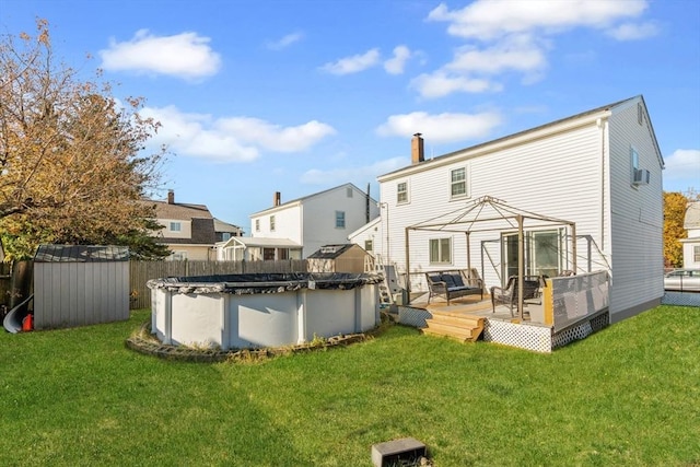 rear view of property featuring a storage shed, a swimming pool side deck, and a lawn