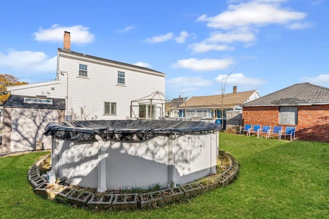 back of property featuring a covered pool and a yard