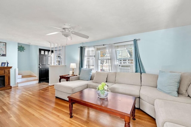 living room featuring ceiling fan, light hardwood / wood-style flooring, and a fireplace