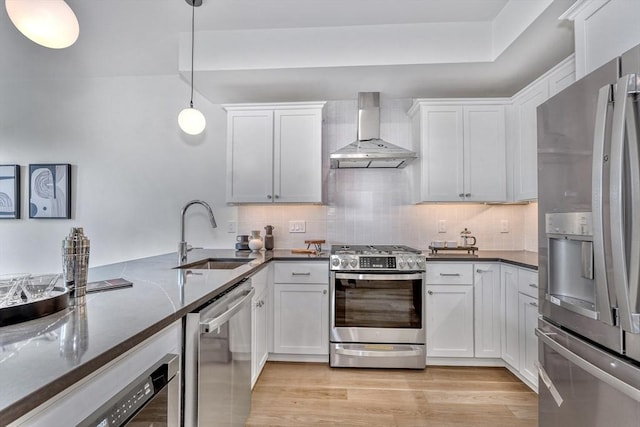 kitchen with a sink, backsplash, appliances with stainless steel finishes, and wall chimney range hood