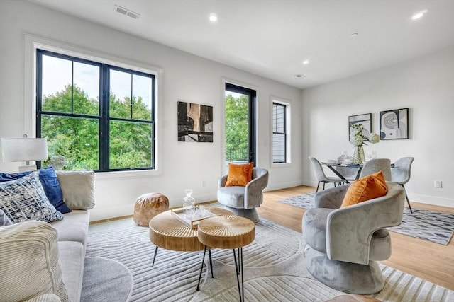 living room with light wood-style flooring, plenty of natural light, and visible vents