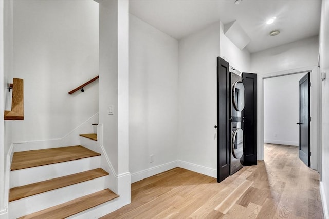 stairs with stacked washer and clothes dryer, baseboards, and wood finished floors