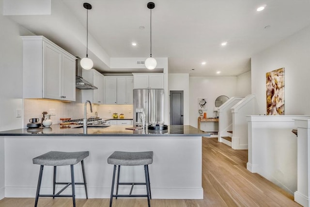 kitchen featuring a peninsula, dark countertops, stainless steel fridge with ice dispenser, and light wood finished floors