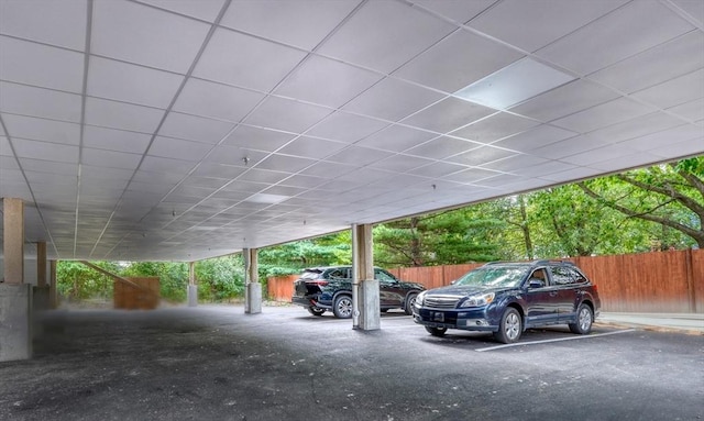 view of vehicle parking featuring a parking garage and fence