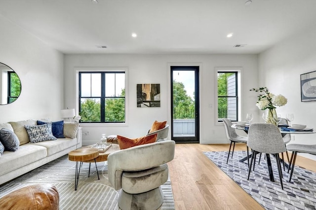 living area with recessed lighting, visible vents, light wood-type flooring, and baseboards