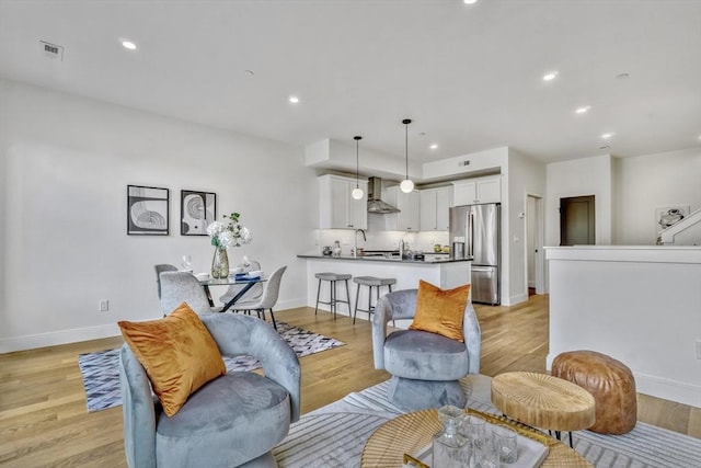 living area featuring visible vents, recessed lighting, baseboards, and light wood finished floors