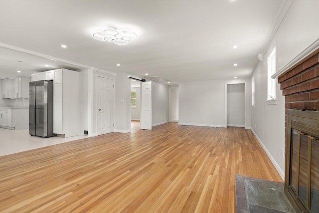 651 S Main St, Randolph, MA 02368 - unfurnished living room with a fireplace, a barn door, plenty of natural light, light wood-type flooring, and recessed lighting