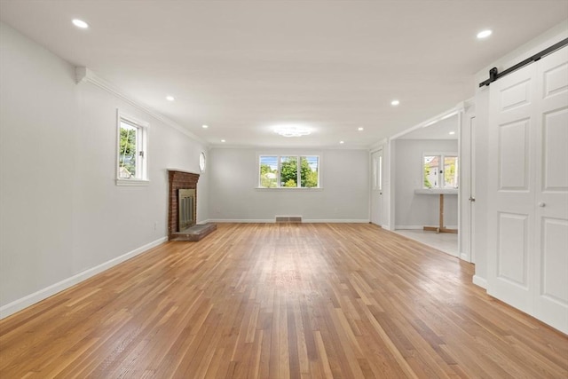 651 S Main St, Randolph, MA 02368 - unfurnished living room with a barn door, light wood-style flooring, ornamental molding, a fireplace, and baseboards