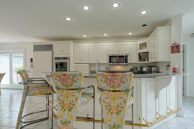 244 Salem End Rd, Framingham, MA 01702 - kitchen with appliances with stainless steel finishes, white cabinets, light tile patterned floors, recessed lighting, and a breakfast bar