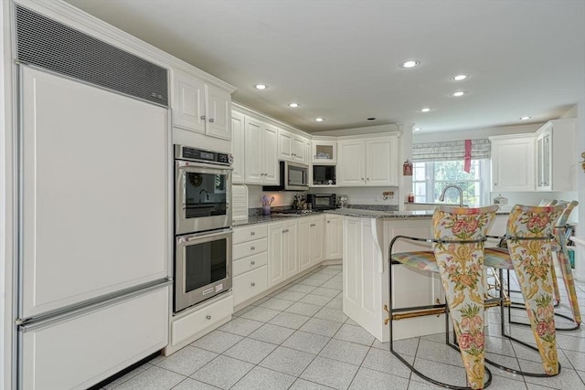 244 Salem End Rd, Framingham, MA 01702 - kitchen featuring stainless steel appliances, recessed lighting, a breakfast bar, light stone countertops, and glass insert cabinets