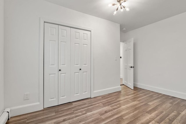 20 Pleasant View Ave, Everett, MA 02149 - unfurnished bedroom with baseboard heating, a chandelier, light wood-type flooring, and a closet