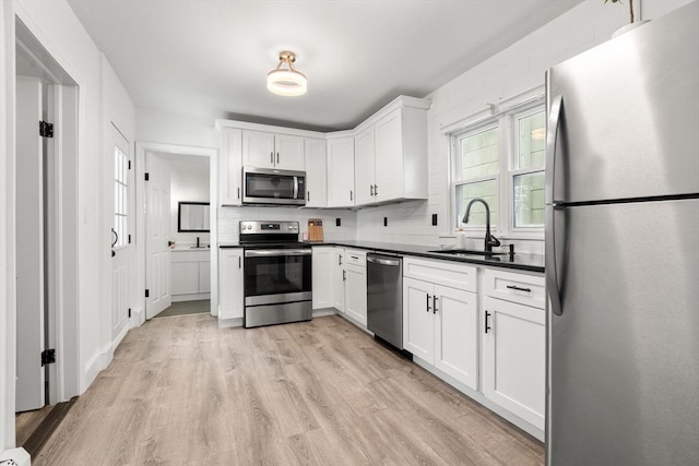 20 Pleasant View Ave, Everett, MA 02149 - kitchen with stainless steel appliances, light wood-type flooring, dark countertops, white cabinets, and backsplash