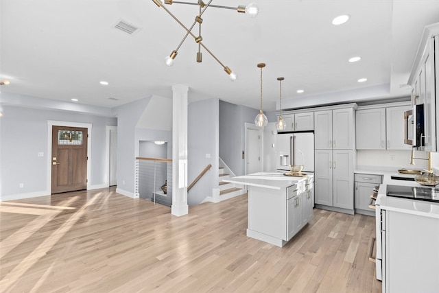 kitchen with gray cabinetry, a center island, white appliances, and light hardwood / wood-style floors