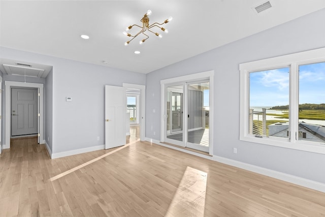 spare room with a notable chandelier and light hardwood / wood-style flooring