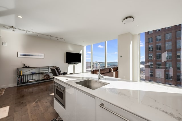 kitchen featuring dark hardwood / wood-style floors, white cabinetry, sink, and track lighting