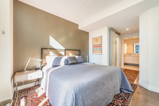 bedroom featuring ensuite bathroom and hardwood / wood-style floors