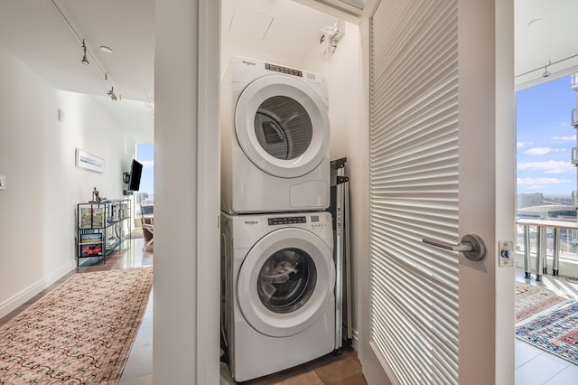 laundry area with track lighting, light hardwood / wood-style floors, and stacked washer / dryer