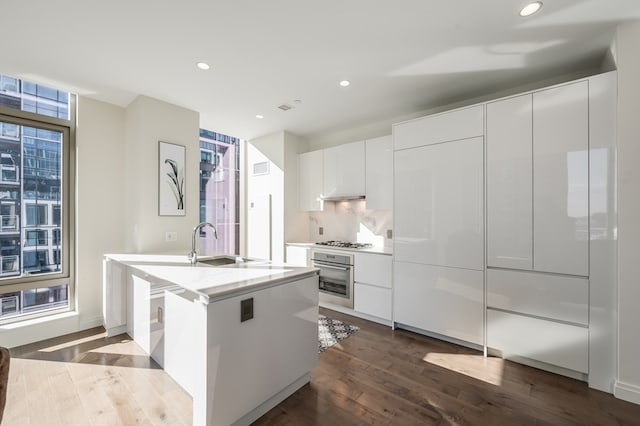 kitchen featuring sink, dark hardwood / wood-style floors, white gas cooktop, oven, and white cabinets