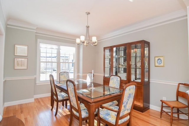 dining room featuring a notable chandelier, light wood-type flooring, baseboards, and crown molding