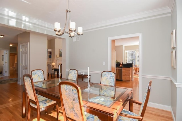 dining space with light wood finished floors, crown molding, visible vents, and a notable chandelier