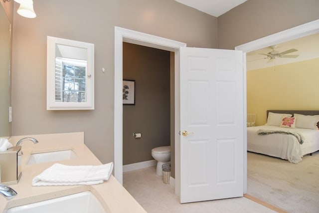 ensuite bathroom featuring baseboards, a ceiling fan, toilet, ensuite bathroom, and a sink