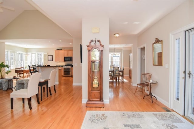 entryway with light wood finished floors, visible vents, baseboards, lofted ceiling, and a chandelier