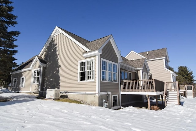 view of snowy exterior featuring roof with shingles, stairs, and a wooden deck