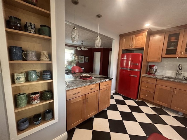 kitchen featuring pendant lighting, sink, fridge, tasteful backsplash, and dark stone counters