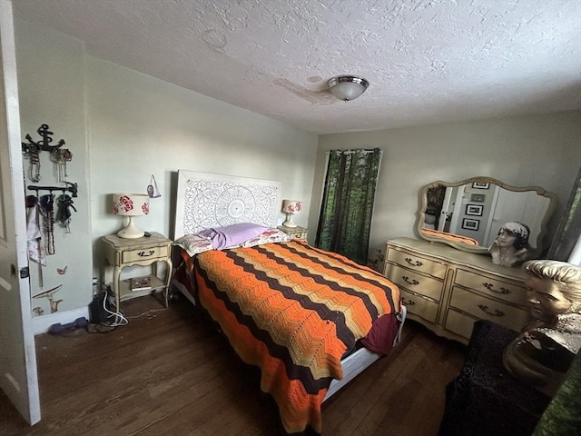 bedroom with dark hardwood / wood-style floors and a textured ceiling