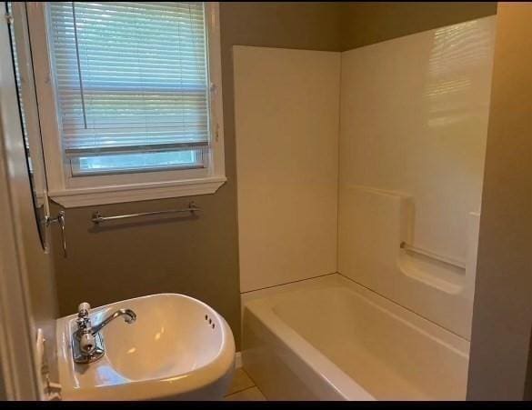 bathroom featuring tile patterned flooring, shower / washtub combination, and sink