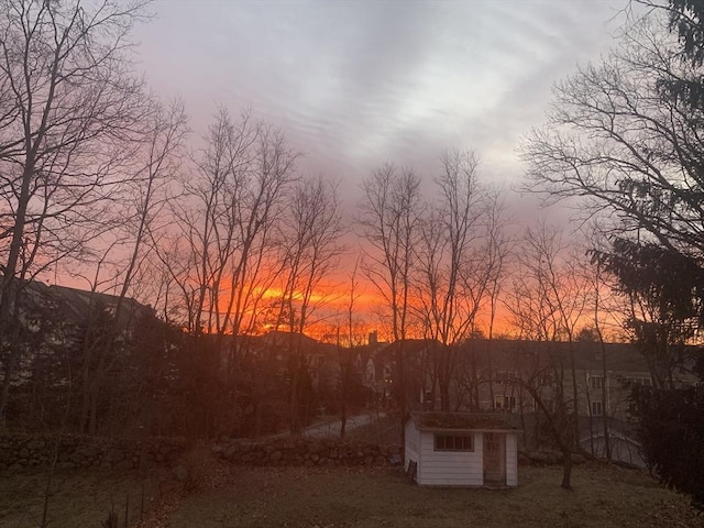 yard at dusk featuring a storage shed