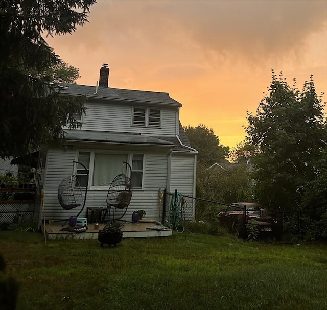 back house at dusk featuring a lawn