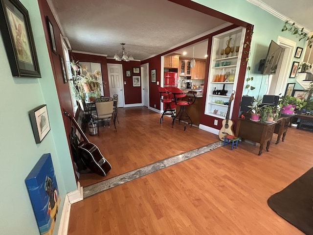 dining space featuring sink, crown molding, built in shelves, an inviting chandelier, and light hardwood / wood-style flooring