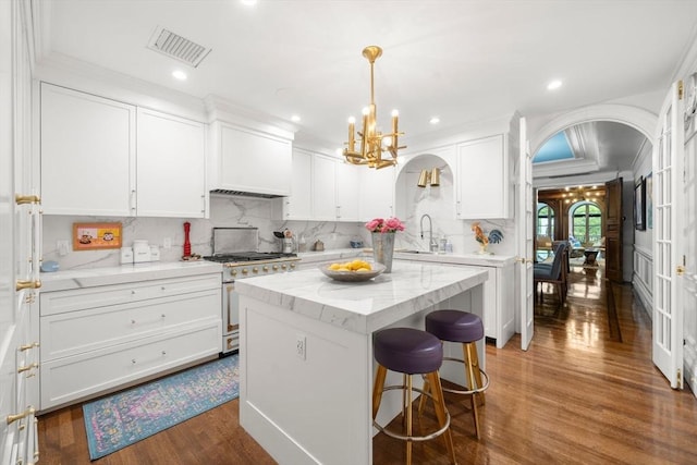 258-260 Beacon St Unit 4, Boston, MA 02116 - kitchen with stainless steel stove, arched walkways, white cabinetry, a chandelier, and dark wood-type flooring