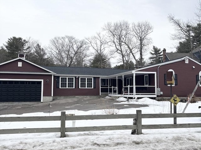 view of front of property with driveway, a chimney, an attached garage, and fence