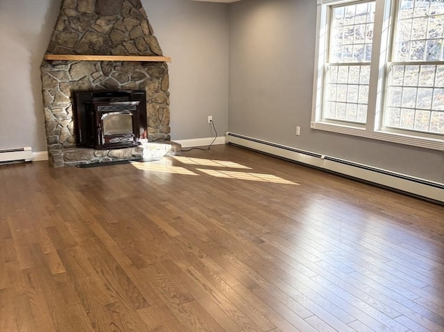 unfurnished living room featuring a baseboard heating unit, baseboards, and wood finished floors