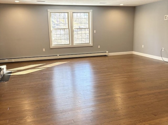 spare room featuring baseboards, baseboard heating, dark wood-type flooring, and recessed lighting