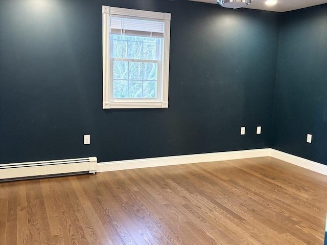 unfurnished room featuring a baseboard radiator, baseboards, and wood finished floors