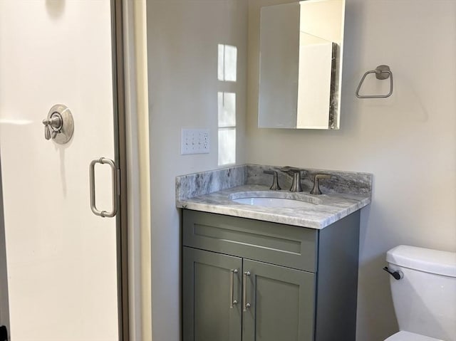 bathroom featuring toilet, an enclosed shower, and vanity