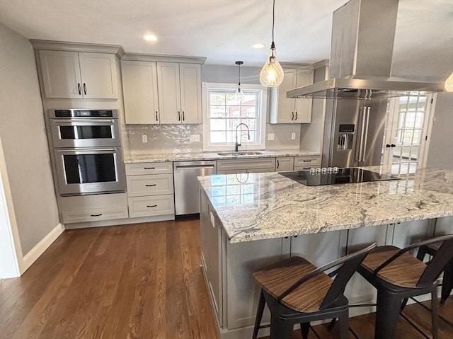 kitchen with dark wood-type flooring, decorative light fixtures, island exhaust hood, stainless steel appliances, and a sink