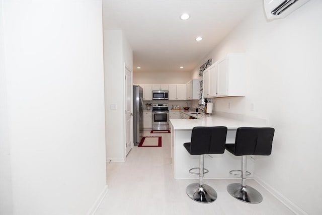 kitchen featuring kitchen peninsula, appliances with stainless steel finishes, sink, white cabinets, and a breakfast bar area